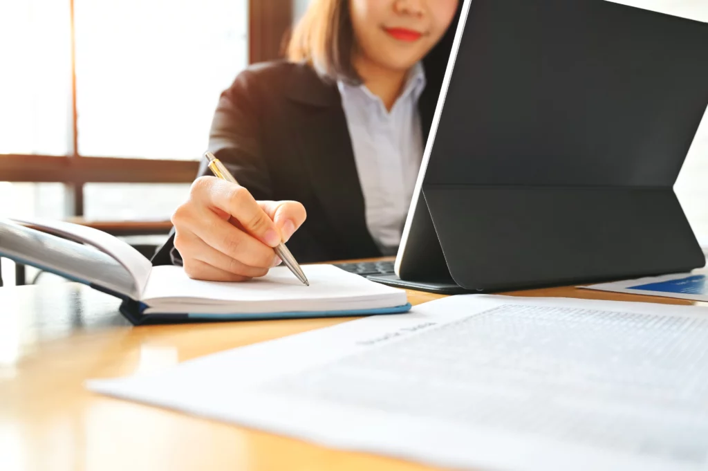 Mujer realizando una auditoría que trabaja con una tableta en el escritorio.