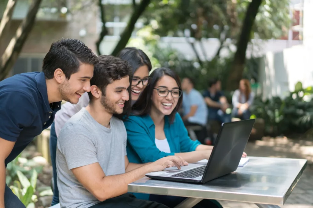 Grupo de jóvenes en un parque viendo un computador